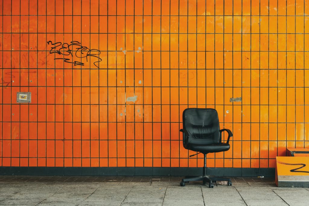 black leather rolling chair beside orange wall photo